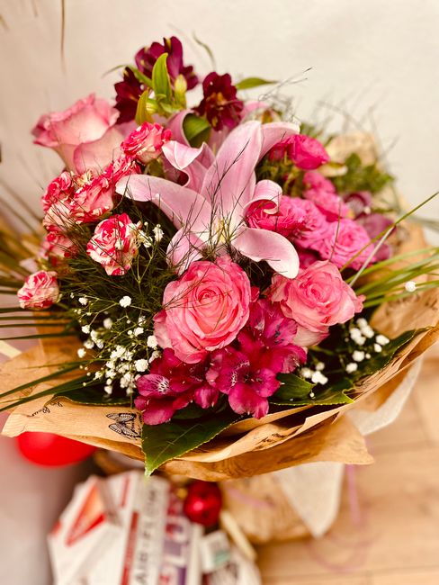 A floral arrangement featuring a variety of fresh pink roses with delicate, tightly packed petals, complemented by white baby's breath and pink alstroemeria with darker pink streaks, all arranged with